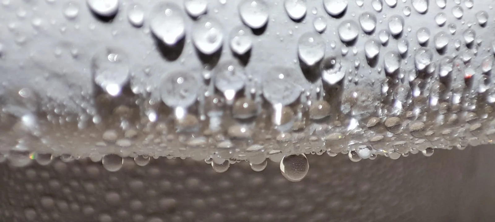 Gotas de agua colgando del faldón de un aislador siliconado sin mojar la superficie